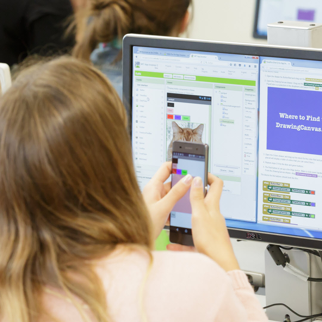 Foto: zwei Mädchen sitzen vor dem PC und 
                        programmieren mit Blöcken die Foto Mal-App