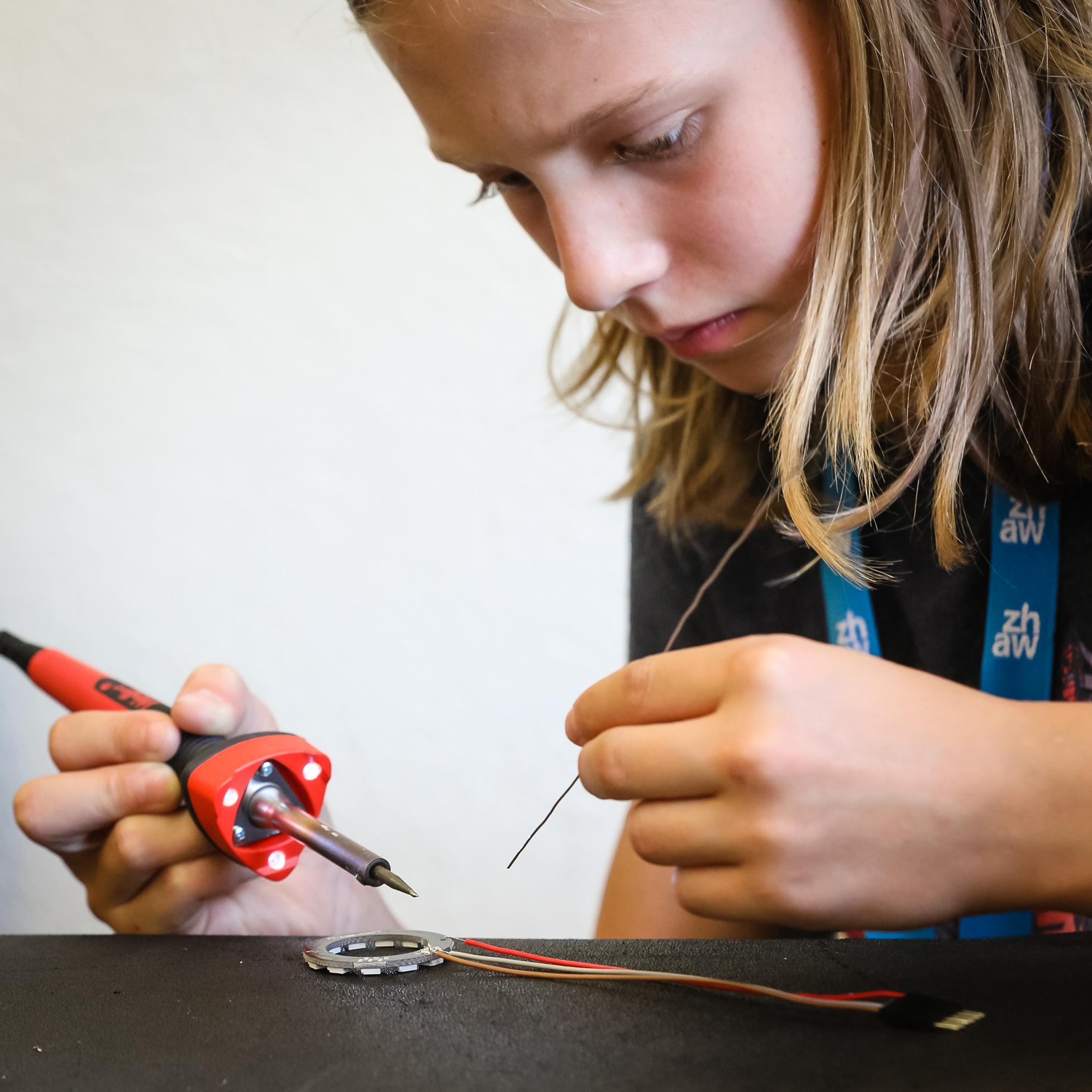 Foto von der Herstellen des LightBags: 
                        Mädchen lötet Kabel an LED-Ring