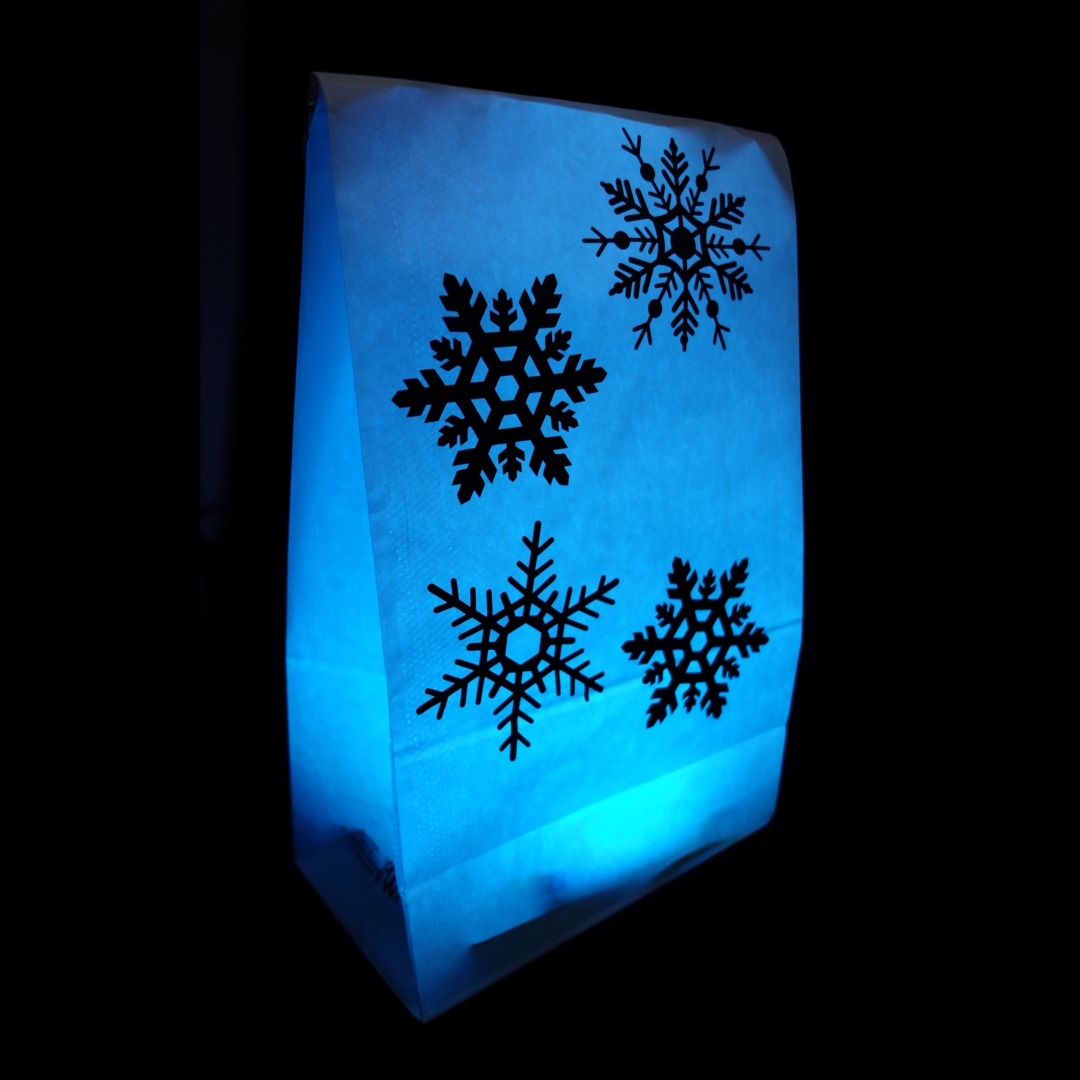 Foto einer LightBag-Dekoration: vier unterschiedliche
                       Schneeflocken aufgeklebt auf einem blau leuchtenden LlightBag